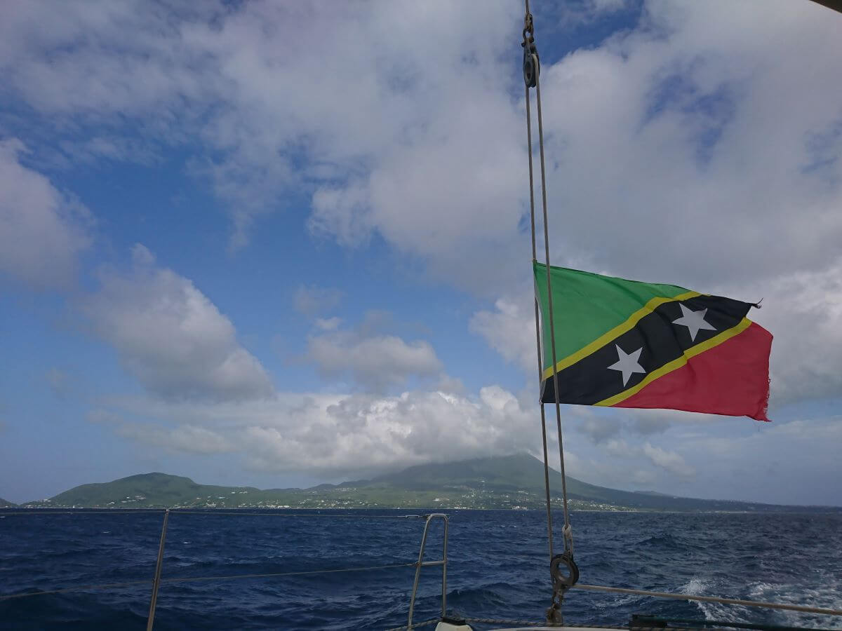 St Kitts and Nevis flag flying on a boat with St Kitts island in the background