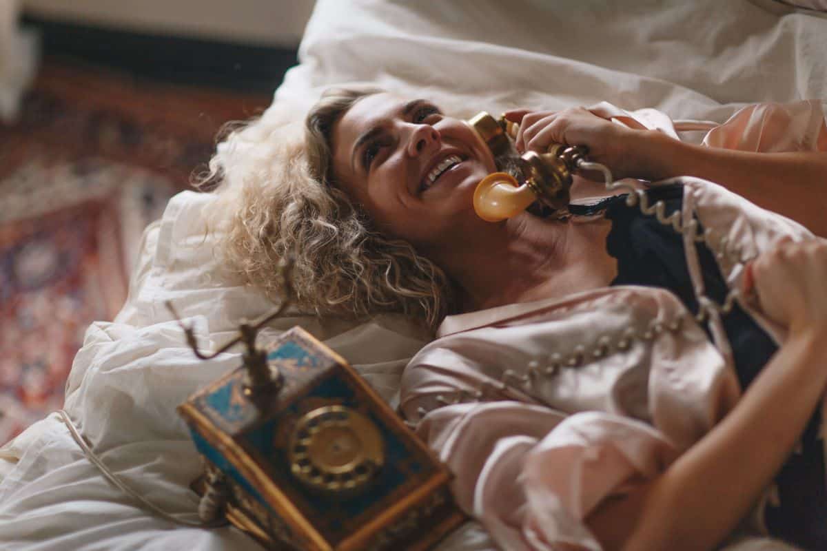 A lady with blonde hair laying on a bed making a telephone call. Telephone calls are a great way to stay connected with friends and family