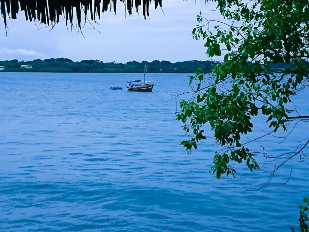 On the water sits a traditional Arab Dhow boat, a large wooden fishing vessel