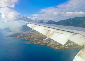 The wing of an airplane is centre of the picture above the Caribbean island of St Kitts. On the island you can see houses and the sea